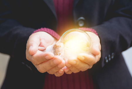 Hand of businesswomean holding light bulb for idea or success or solar energyの写真素材