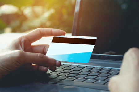 Hands holding blue credit card and using a laptop for online shopping concept.の写真素材