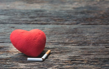 Heart and cut off cigarette on wooden background. Protect your health concept.の写真素材