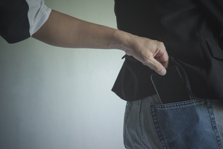 Close-up of a the hand of thief stealing the wallet to a woman. Thief stealing wallet from back pocket of a woman.の写真素材