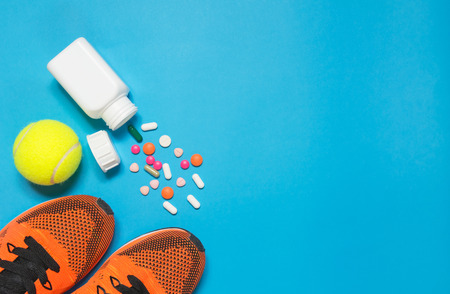 Concept preparing to fitness sports equipment and bottle of medicine on blue background.の写真素材
