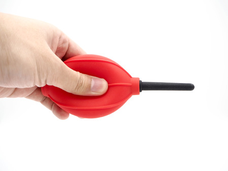 Hand squeezing a red camera air blower isolated on a white background.の写真素材
