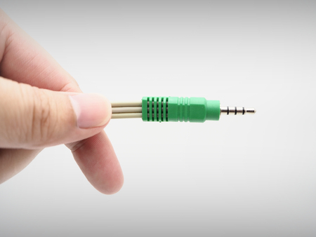 Hand holding a jack instrument cable on a white background.の写真素材