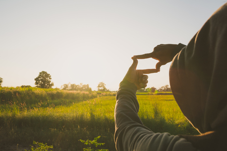 Hands making frame with sunset. Close up of woman hands making frame gesture.の写真素材