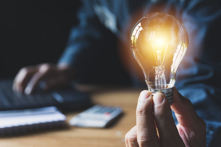 Hand of male holding a light bulb for accounting and creative concept.の写真素材