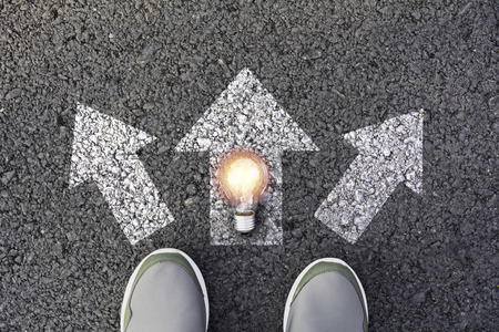Shoes standing  and light bulb at the crossroad and get to decision which way to go. Ways to choose concept.の写真素材