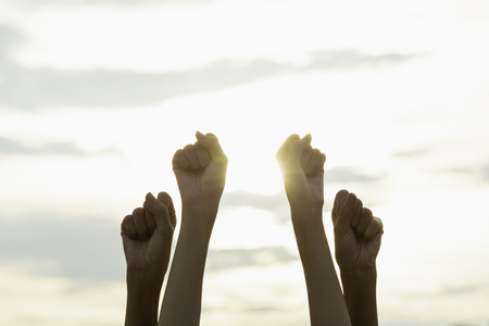 Hand of people fist raising up showing power strong with sky background.の写真素材