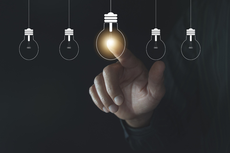 Innovation or creative concept of finger touching a light bulb and copy space for insert text.の写真素材