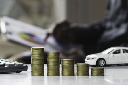 Car insurance and car service. Line graph with stack of coins and toy car, business and financial concept.の写真素材