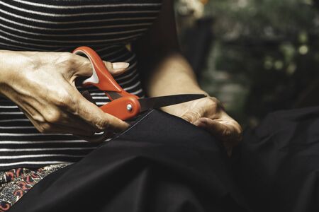 Woman cutting black fabric with scissors. Housework and lifestyle concept.の写真素材