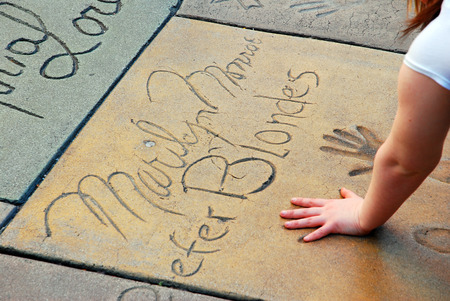 A Young Woman Puts Her Hands in Marilyn Monroe Handprints, Chinese Theater, Hollywoodのeditorial素材