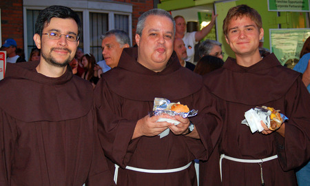 Three monks nosh on sausage and pepper hero at a festival in Boston's North Endのeditorial素材
