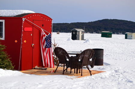 Patio furniture is set up in an unlikely location: outside of an ice fishing shack on Lake Winnipesaukee, New Hampshireの写真素材
