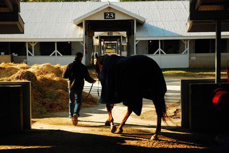 A Trainer leads a horse back to the stable at Keeneland Race Track in Lexington, Kentuckyのeditorial素材