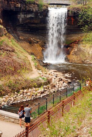 A young couple gazes at the power of Minnehaha Falls near Minneapolis, Minnesotaのeditorial素材