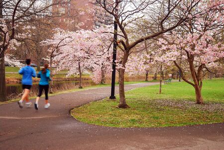 A couple runs in the Boston Esplanade on a cloudy spring dayのeditorial素材