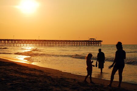 A family plays at the shoreline at sunrise at Myrtle Beachのeditorial素材