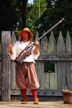 A costumed re-enactor demonstrates a colonial era gun in Jamestown, Virginia