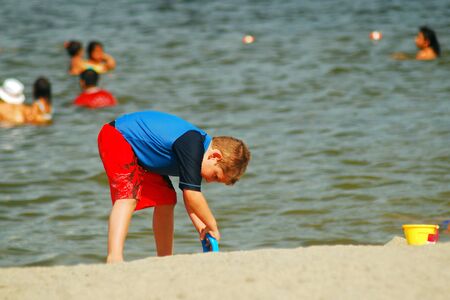 A young boy digs at the beachのeditorial素材