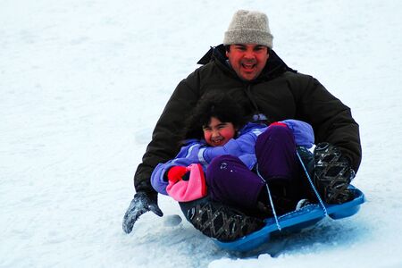 A father and daughter enjoy sledding in winterのeditorial素材