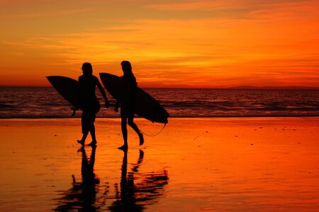 Two teenager surfers leave the ocean at the day's endのeditorial素材