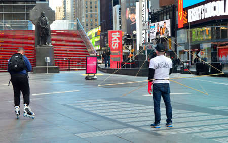 A rollerblader avoids a man demonstrating social distancing in an empty Times Squareのeditorial素材