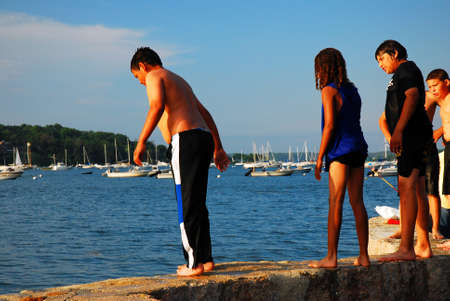 A group of kids survey the waters before decidiing to jumpのeditorial素材