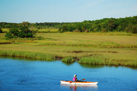 An adult man kayaks through a salt marsh on Cape Codのeditorial素材