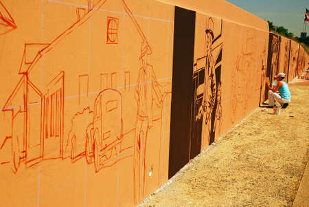 A young woman adds detail to a mural painted along Interstate 35 in Denton, Texasのeditorial素材