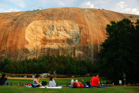 People hold a picnic under a large granite carving of Confederate Generals in Stone Mountain, Georgiaのeditorial素材
