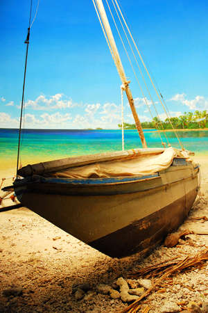 A traditional Polynesian sailboat sits on the shore of a tropical beachのeditorial素材