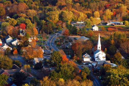 Autumn foliage surrounds a quaint New England townの写真素材
