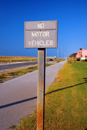 A sign on a bike path reminds folks to keep cars on the roadの写真素材