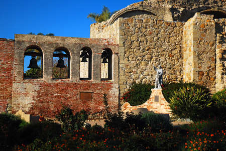 A bell tower and stone wall are the remaining pieces of the original Mission San Juan Capistrano in Californiaの写真素材