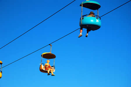 A whimsical caveman manikin rides the Sky glider over the Boardwalk in Santa Cruz, Californiaのeditorial素材