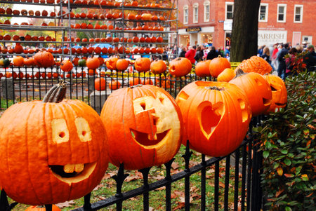 Pumpkins are placed to an iron fence, like heads on a stake, at a pumpkin festival in New Englandのeditorial素材