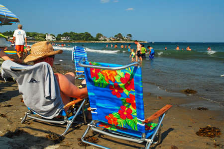An adult man relaxes in his beach chair along the shoreのeditorial素材