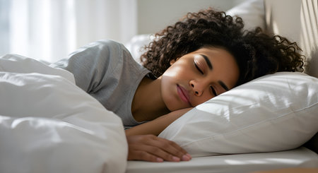 Peaceful sleep portrayed by a woman resting comfortably in bed with curly hair. Relaxation and tranquility in bedroom setting for home lifestyle concept. Serene dream state in soft light with sleeping beauty atmosphere. Focus on comfort and rest with emphasis on peaceful sleep. Woman sleeping peacefully in bed.の素材