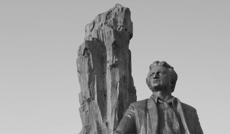 A stone statue of a man against a white sky. The black and white pictureの写真素材