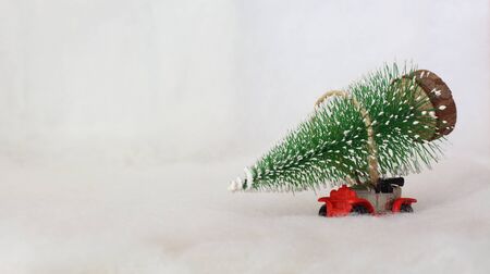 Toy car carrying a Christmas tree in a snowy landscape. Space for text.の写真素材