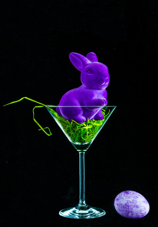Lilac Easter Bunny and egg in a glass on a black background