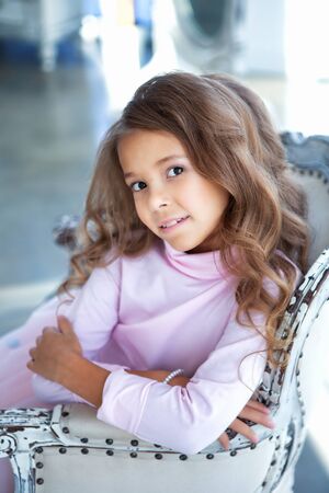 Happy little girl is sitting in the light studioの写真素材