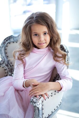 Happy little girl is sitting in the light studioの写真素材
