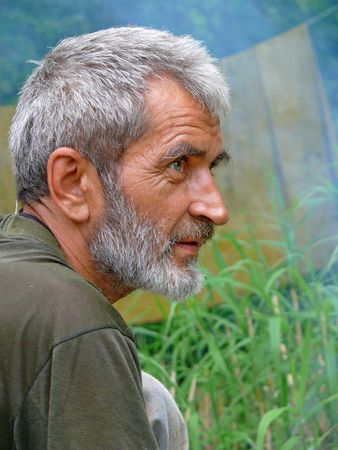 A portrait of the weather-burned man with grey beard and intent look. Profile. Russian Far East, Primorye.の写真素材