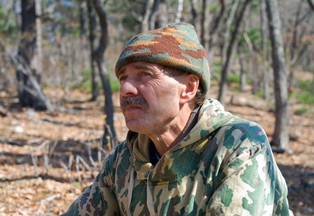 A man in camouflage suit is in forest. Autumn, sunny day.の写真素材