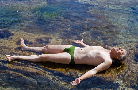 A man sunburns in water among reefs. Summer, sunny day.の写真素材