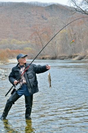 A man on fishing with fish on hook.の写真素材
