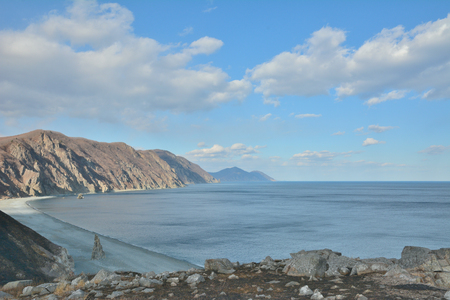 A landscape on sea-coast with rocks, beach and clouds.の写真素材