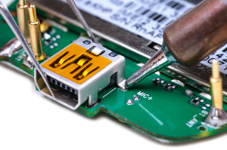 Electronic technician repairs mini USB socket on mobile phone circuit board  Close-up with selective focus and Shallow Depth of Field  Isolated on white background  の写真素材