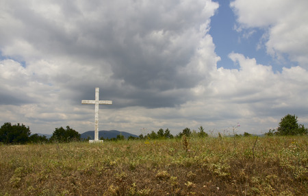 Old cross in the field against blue sky の写真素材